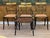 A set of four English Regency period black lacquer dining chairs with gilt decoration throughout consisting of three side...