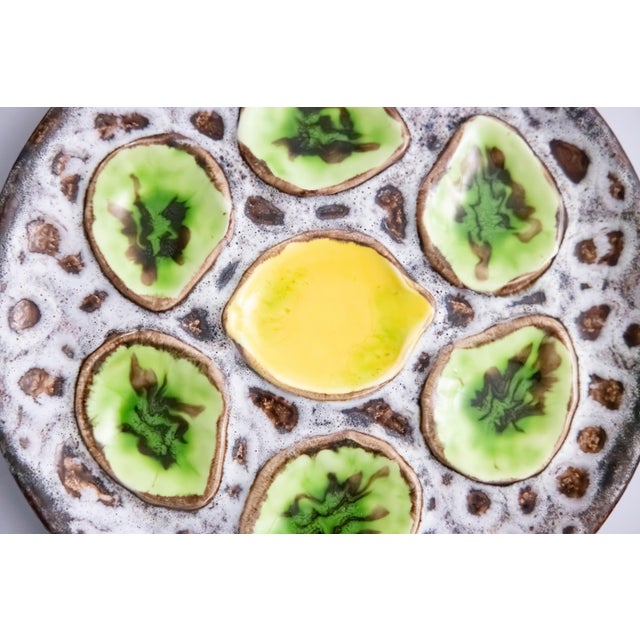 A vibrant Mid-Century French green and yellow majolica oyster plate in the Vallauris style, six wells with a lemon center.
