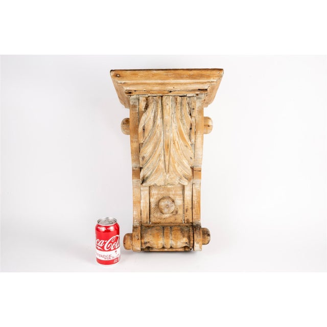 A large salvaged architectural stripped wooden hand-carved corbel with natural grain, nail holes and old repairs, a flat...