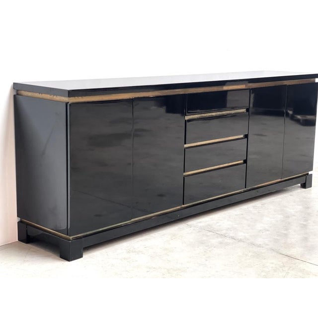 Luxurious seventies glamour sideboard by Jean claude Mahey consitsing of black lacquer panels and brass. The use of...