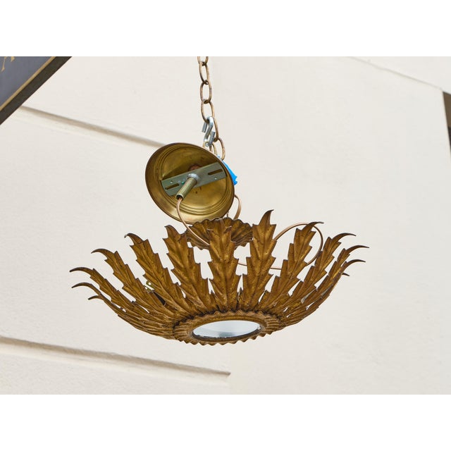Radiating with sculptural flair, this Spanish gilt metal light fixture from circa 1950-1960 takes inspiration from...