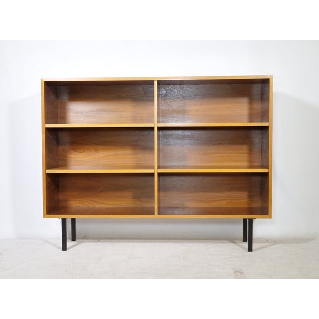 Minimalist mid-century shelving unit in teak veneer with black metal legs, 1960s. The open rectangular body is divided...