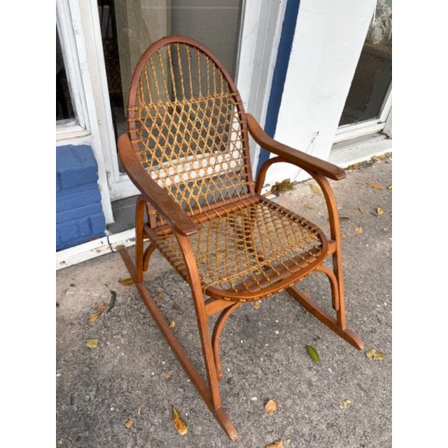 The 1970s Vintage Snowshoe Oak Rocking Chair by Vermont Tubbs is a fully assembled antique chair made of brown oak....