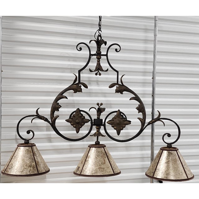 Large wrought iron and bronze accented chandelier pendant by Ironware International, Inc. The three lights volute...