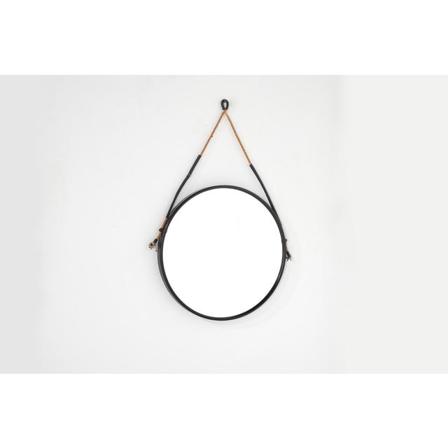 Vintage round mirror in matte black painted metal, suspended by a leather cord. Italy, 1970s. Production period: 1970s....