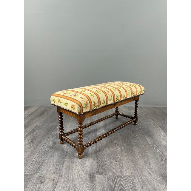 Charming antique bench resting on an elegant turned wood base in the "barley twist" style, connected by a similarly...