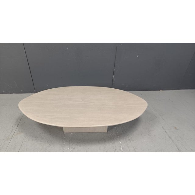 Elegant travertine coffee table with an oval table top resting on a rectangular base. This timeless piece adds a touch of...