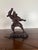 A dramatic Japanese bronze sculpture depicting a powerful samurai warrior captured mid-motion in a dynamic battle stance....