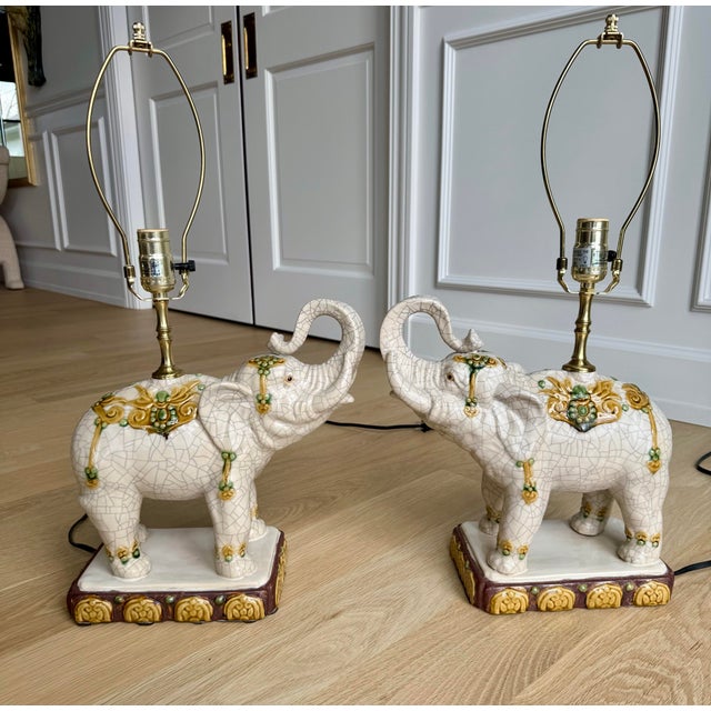 Charming pair of vintage Hollywood Regency elephant table lamps. These stately pieces feature a beautiful cream-white...