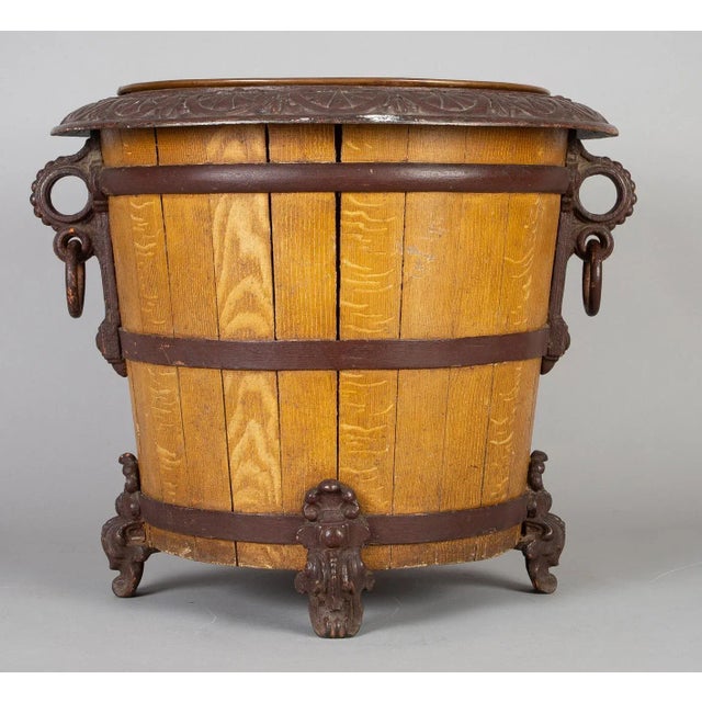 Cast iron and wooden jardinière or log container in barrel form with a copper liner, tapered wooden staves bound by cast...