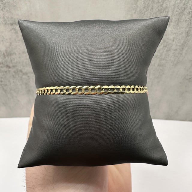 This curb link bracelet is crafted in solid 14kt yellow gold and features a classic interlocking link design with a...