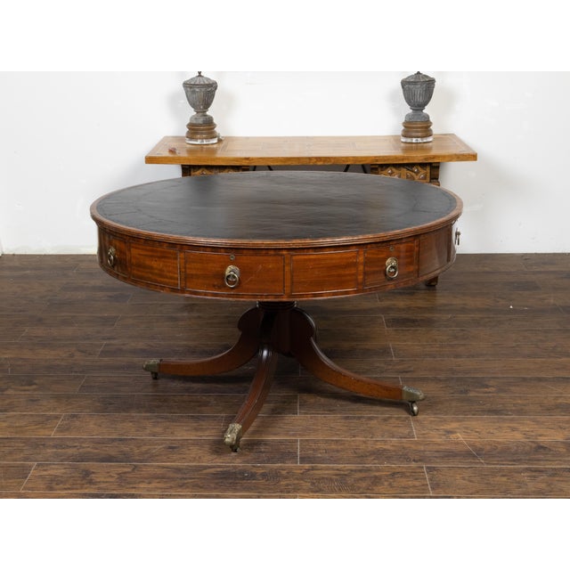 An English Regency period mahogany drum or rent table from the early 19th century, with black leather top, eight drawers,...