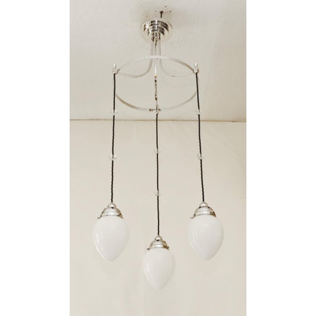 Art Nouveau chandelier, circa 1915. Three olive-shaped opal glass shades. Decorative glass spheres. The lamp has been...