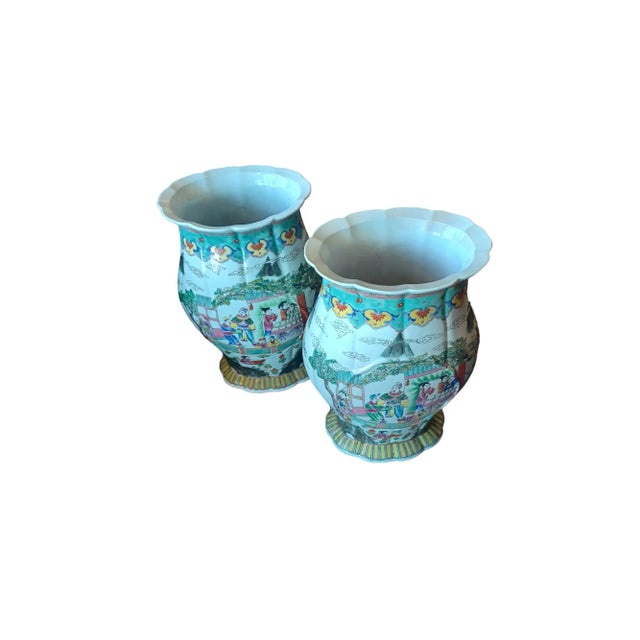 Vintage pair of large ceramic Asian vases with emperor and village scenes surrounding exterior. Vases have a small...