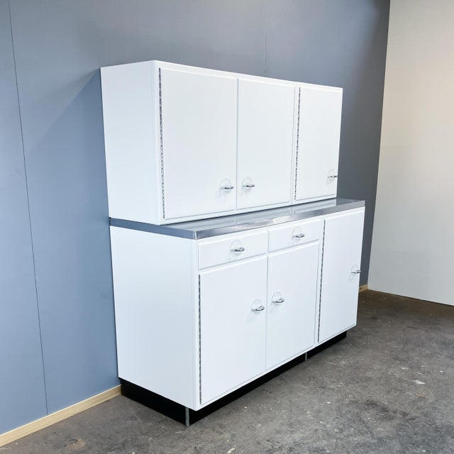 A fully restored kitchen unit, originally made in germany, featuring beautiful contrasts of matte white, a black base, and...