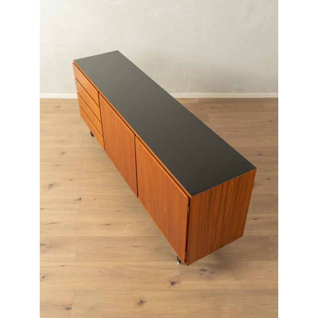 Classic sideboard by Omann Jun. from the 1960s. Teak veneer body with four drawers, two doors, two shelves, an internal...