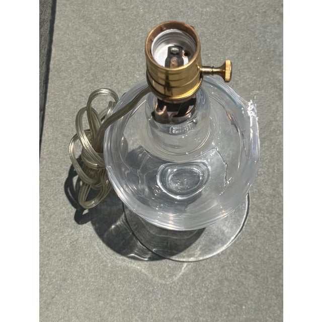 An elegant clear glass lamp in the style of Simon Pearce, known for his timeless hand-blown glasswork from Vermont. The...