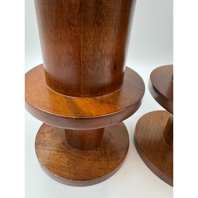 Pair of West Elm solid wood candlesticks featuring a sculptural turned spool form in a rich walnut-tone finish. Clean...