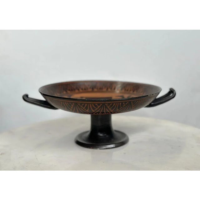 Set of two traditional greek ceramic attic ware serving pieces, consisting of a kylix and saucer plate. Each of these is...