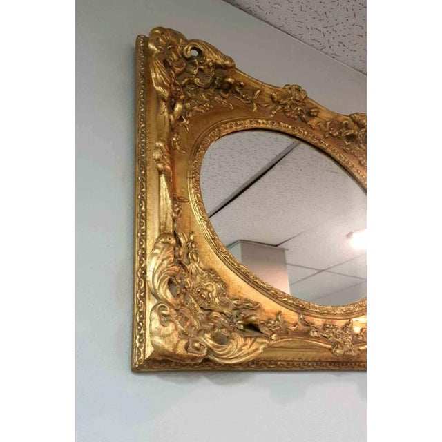 Oval mirror with ornate gold gilded and solid carved wood frame.