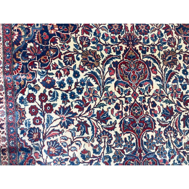 A beautiful antique Persian Dabir Kashan, handwoven around 1920, featuring an elegant ivory field adorned with intricate...