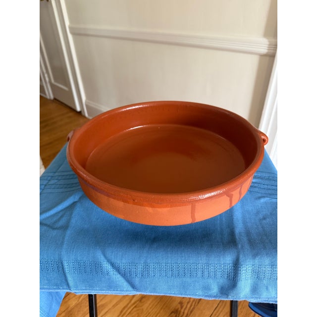 Beautiful vintage terracotta cazuela-style serving dish with a warm reddish-brown glaze. The large, 13" dish features 2...
