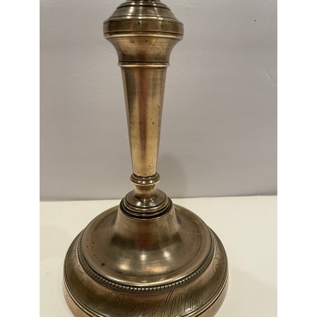 Antique brass baluster-form candlestick, engraved with naturalistic forms on the candle cup, with a scrolling design on...