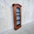 Striking antique wall-hanging display cabinet featuring an exceptionally tall, narrow profile, warm wood finish and an...