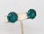 Early to mid 1950s round goldtone unfoiled open backed flawed faux-emerald clip earrings. Marked crown "TRIFARI" on the...