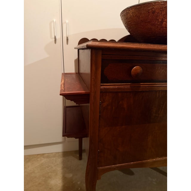Vessel sink bowl affixed to Queen Anne style wooden cabinet with tall faucet and plumbing pipe hookup. Bowl is a deep...
