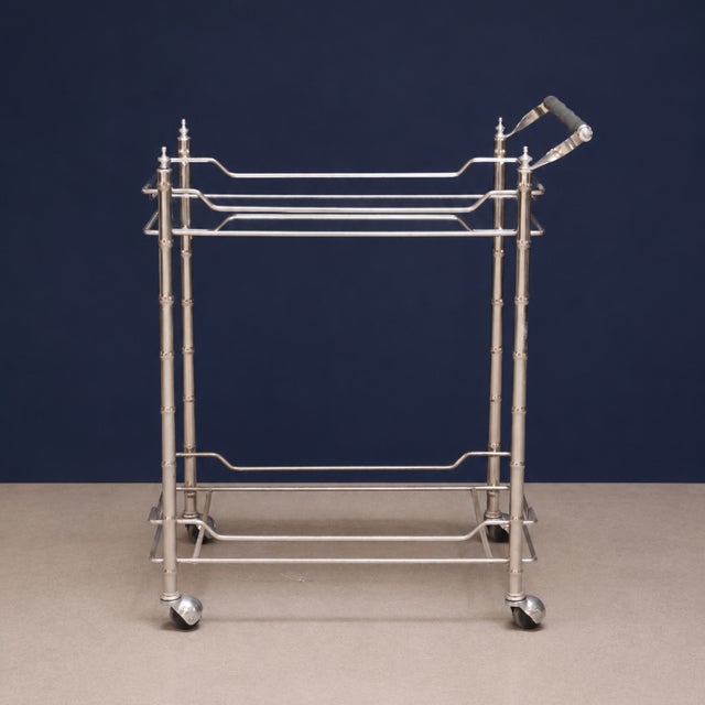 This features a refined open-frame design with slender, bamboo-inspired supports, polished metal rails, and elegant finial...