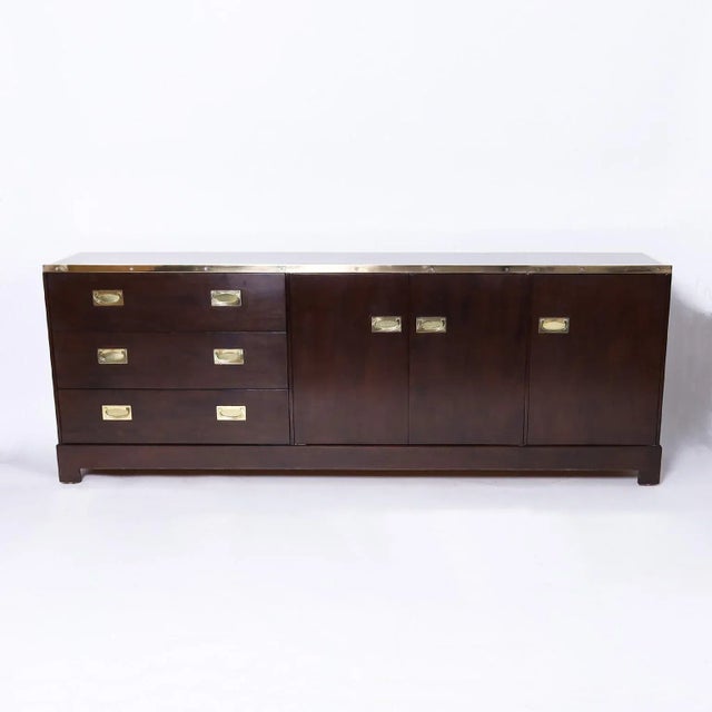 Chic mid-century chest or cabinet crafted in mahogany featuring multiple components including brass campaign style...
