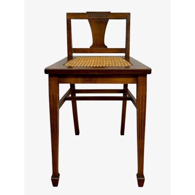 This vintage wooden side chair features a clean, rectilinear frame with a hand-woven cane seat and a distinctive shaped...