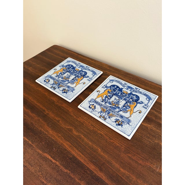 A classic pair of Dutch Delft-style hand painted blue and white porcelain tiles featuring an intricately rendered heraldic...