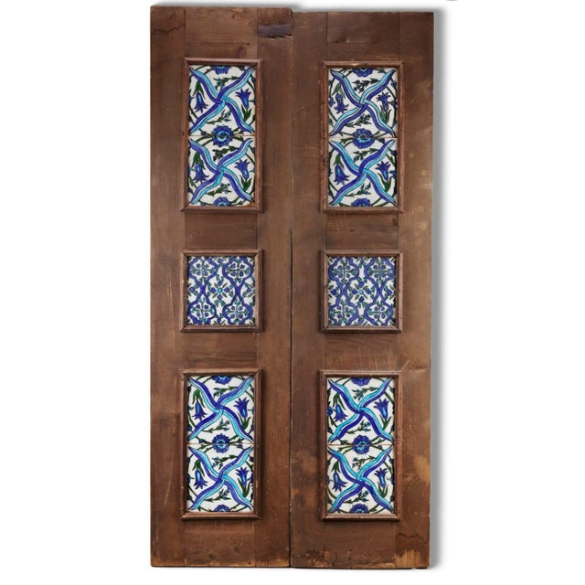 Paired tile designs in cobalt, turquoise and green set in an old wooden door Comprising ten tiles, each pair with varying...
