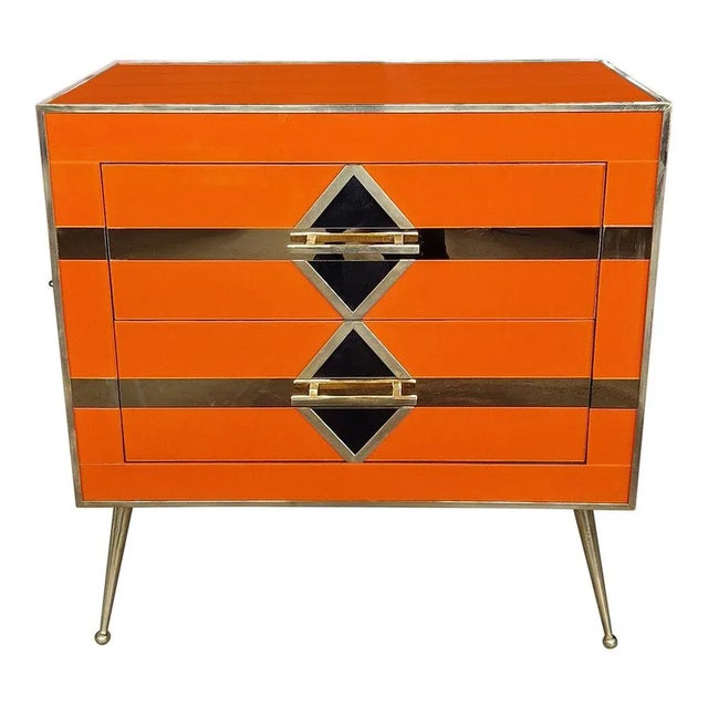 Bedside table entirely handmade, with wooden structure covered in orange glass; profiles, handles and feet in golden...