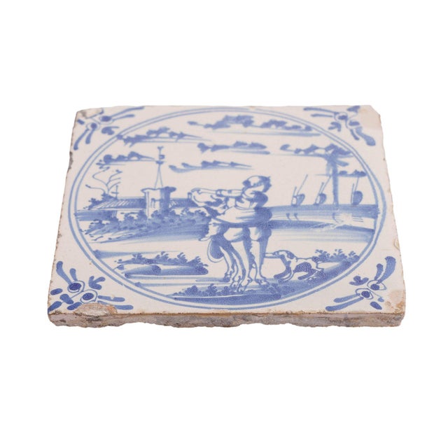 A rare Delft faience scenic narrative tile of a girl astride a farm animal directing a dog back to the farm. The scene is...