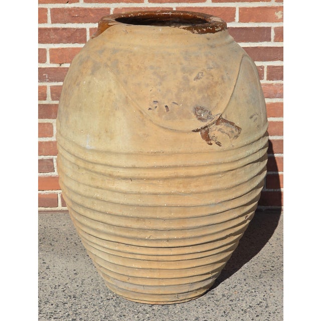 Large Mediterranean olive jar in a buff surface with nice horizontal texturing to the body. There is a brown glaze rim...