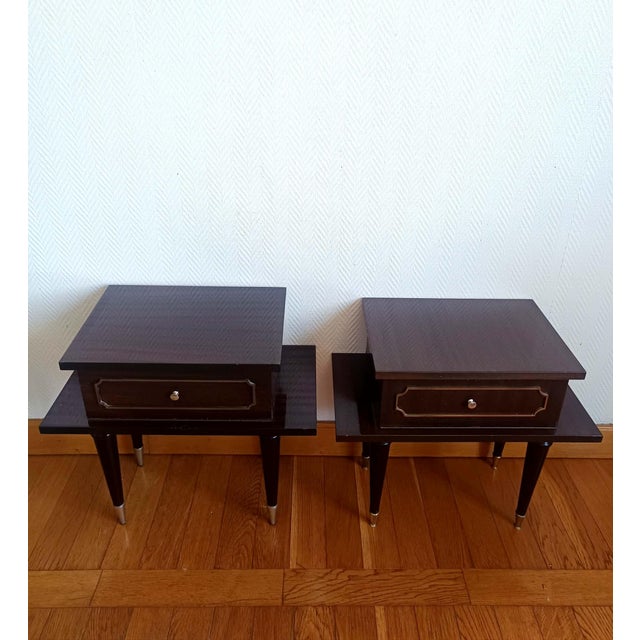 Pair of bedside tables in dark lacquered wood. The lower shelf is wider than the upper one. The front opens with a hinged...