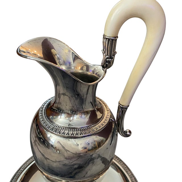 A fine 19th Century Continental silver wine pitcher with under plate. The pitcher is Neoclassical in form with a scrolled...