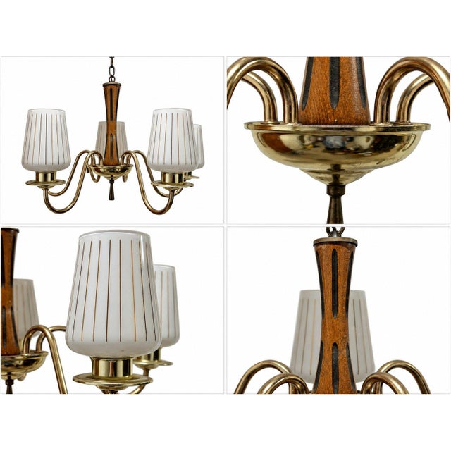 The fixture features a polished metallic frame with gracefully curved arms, a warm wooden central column with dark...