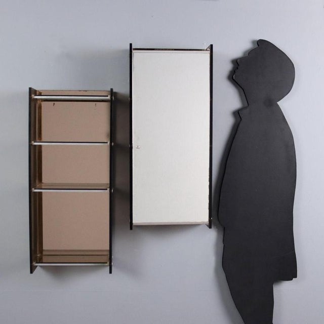 Metal wall units, one with shelves and the other with a mirrored door. This piece is attributed to the mentioned...