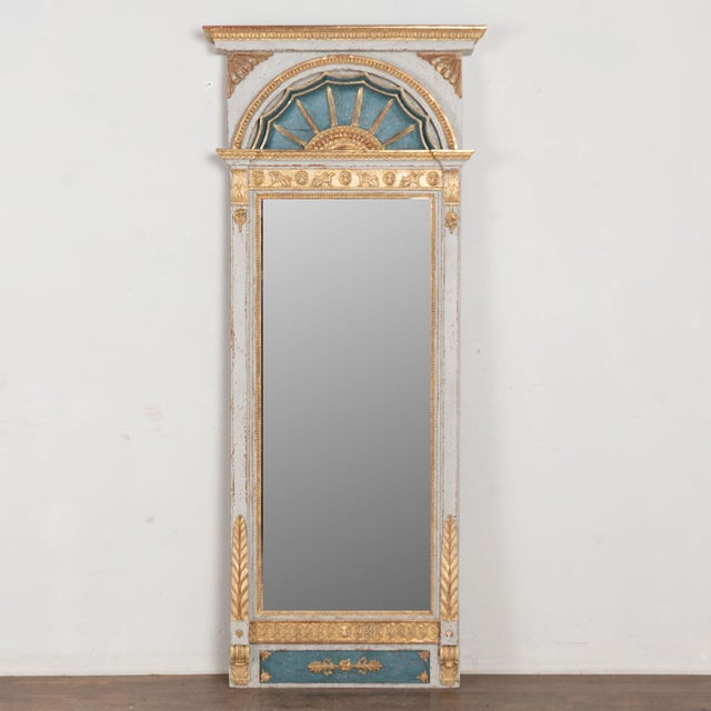 19th-century Swedish trumeau mirror crafted in wood with a gold gilt finish set against a gray and blue painted...
