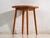 This vintage round side table in teak wood is a three-legged table with a circular top and tapered legs splayed outward....