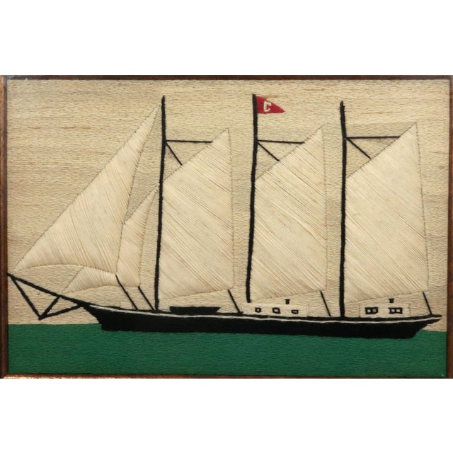 A charming British sailor's woolwork picturing a three-masted schooner in broadside profile, her fore-and-aft sails set...