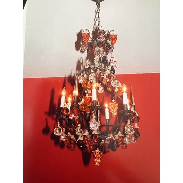 A Louis XV-style wrought iron and colored glass, six light chandelier. The wrought iron frame issuing six scrolling arms...