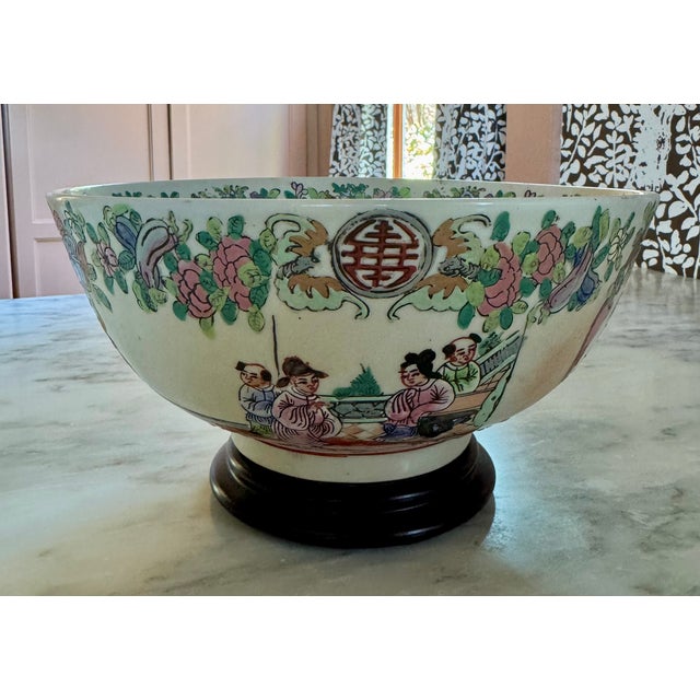 Vintage Chinese Famille Rose porcelain punch bowl featuring hand-painted floral borders and a central court/interior...