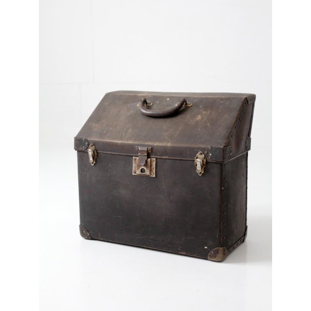 This vintage industrial travel case features a distinctive slant-top form with riveted metal construction, reinforced...