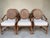 A set of six vintage rattan dining armchairs featuring classic oval cane backs and solid rattan frames with traditional...