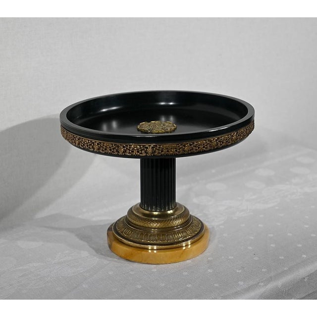 Flat bowl on foot in dark green sheet metal. The interior is decorated with a flower motif in bronze. The outer rim is...